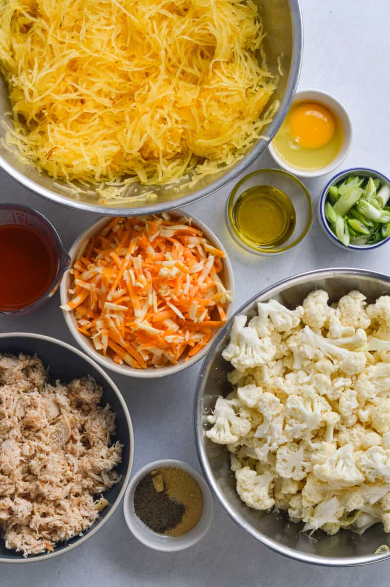 Ingredients including spaghetti squash, cheddar cheese, cauliflower, shredded chicken, green onions, egg, olive oil and buffalo sauce.
