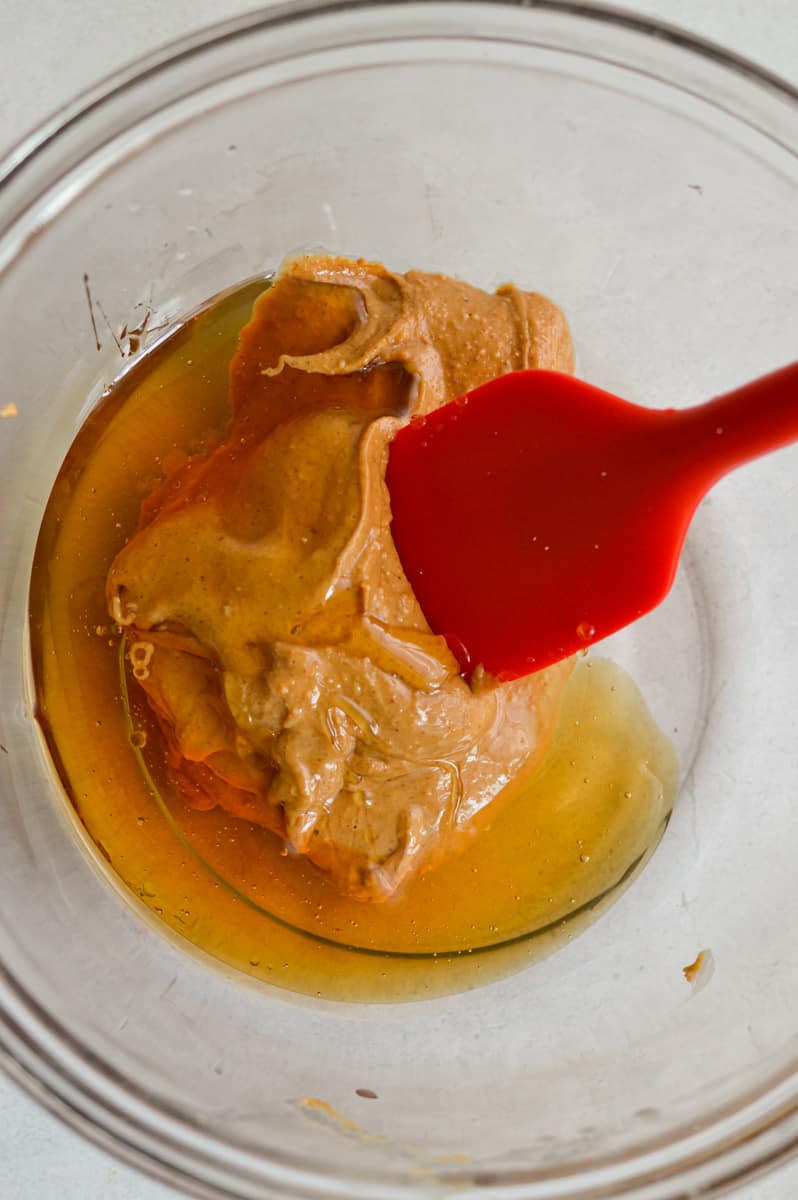 Mixing honey and peanut butter with a spatula.