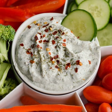 Dunking a cucumber into herb and garlic cottage cheese dip.