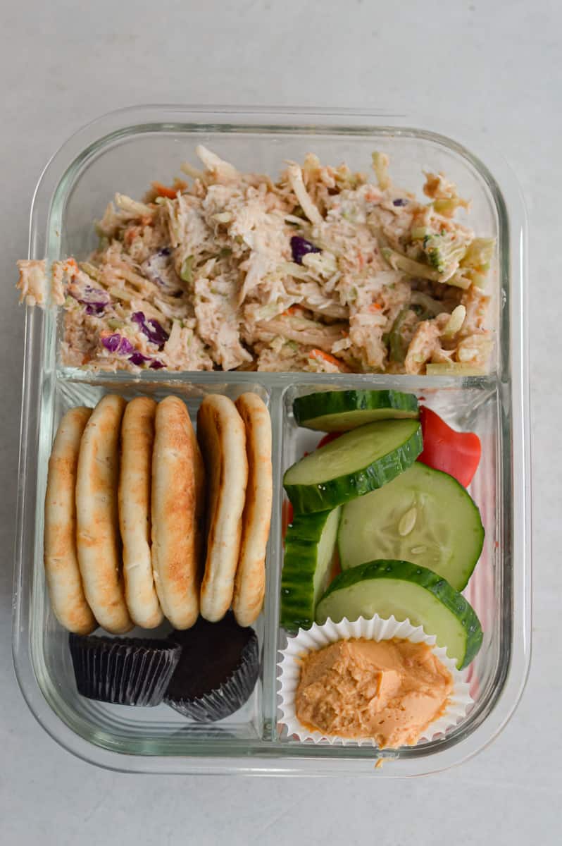 Making an adult lunchable with shredded chicken salad recipe, cucumbers, pita, chocolate and dip.