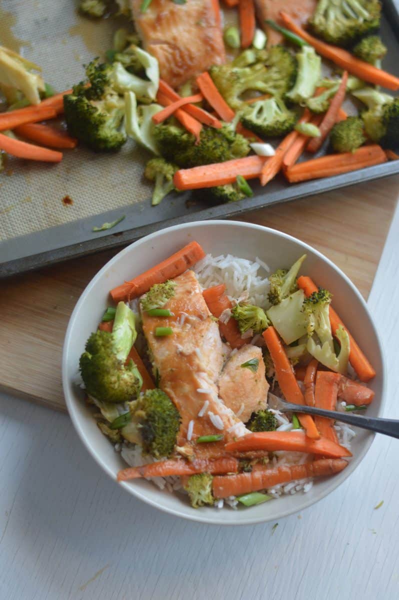Sheet pan salmon and veggies in a bowl with rice.
