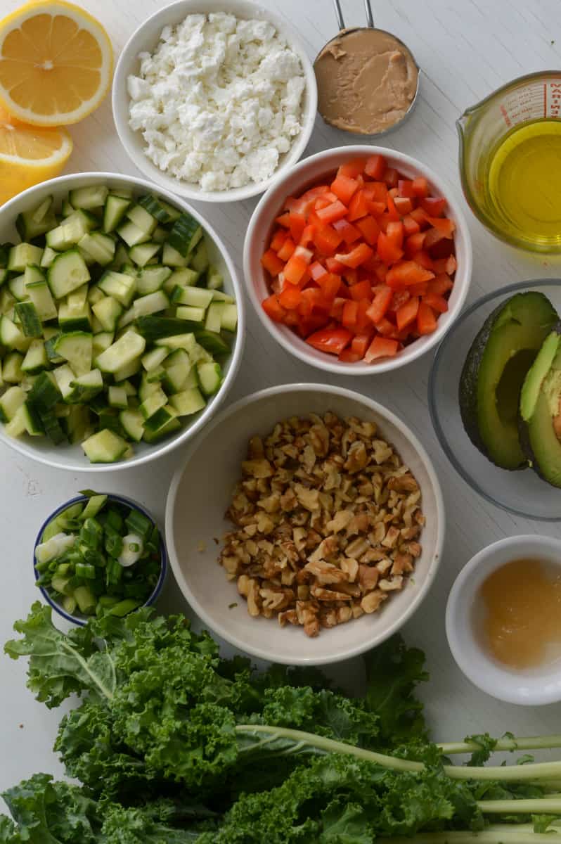 Ingredients for tahini kale salad including kale, walnuts, cucumber, feta, walnuts and lemon.