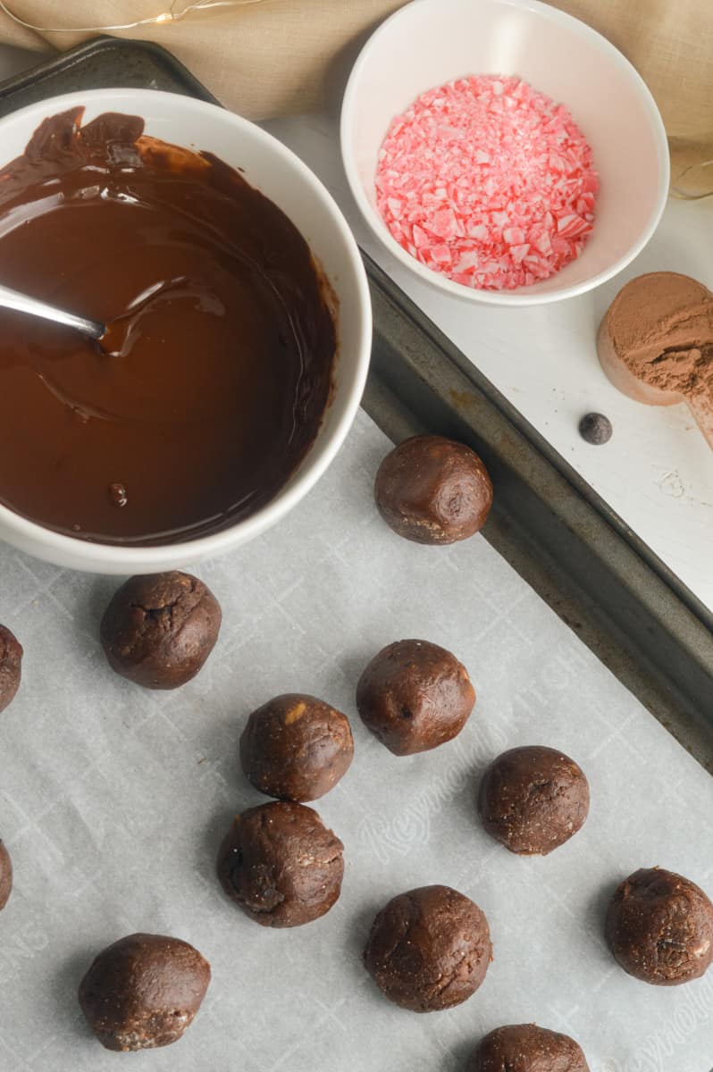 Protein truffles rolled in balls, with a bowl of melted chocolate to be drizzled on top.