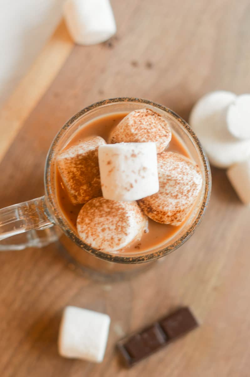 Birds eye view of oat milk hot chocolate with marshmallows and cocoa powder.