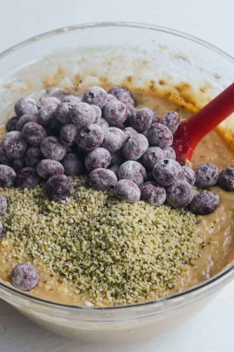 Stirring blueberries and hemp seeds into muffin batter.