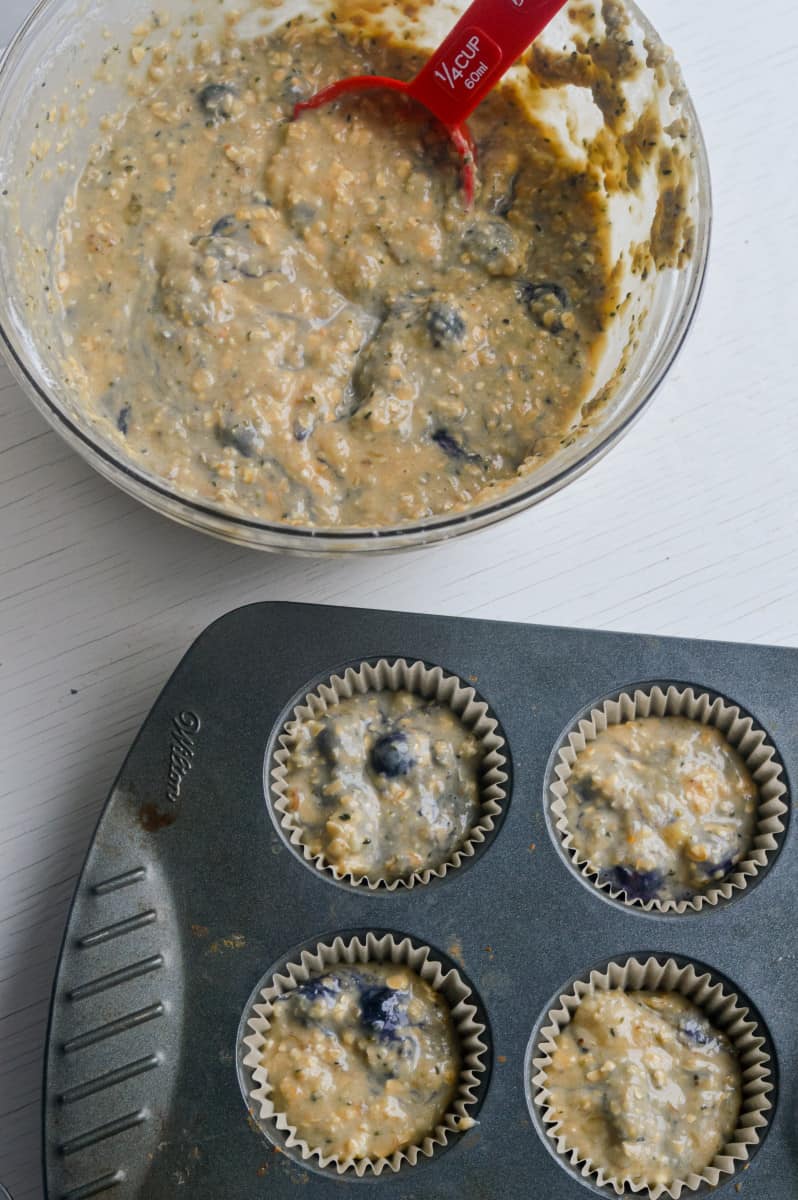 Spooning muffin batter into lined muffin tin.