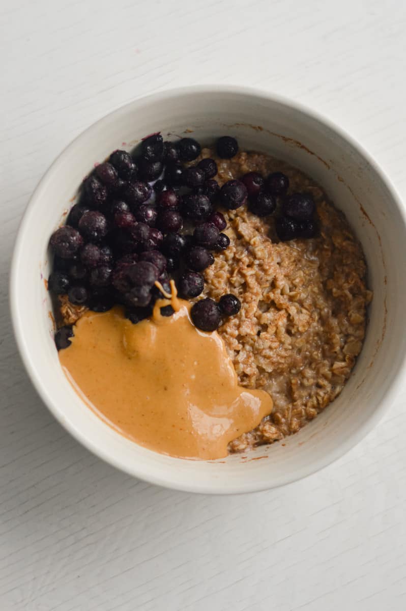 Birds eye view of microwave egg white oatmeal with peanut butter and blueberries.
