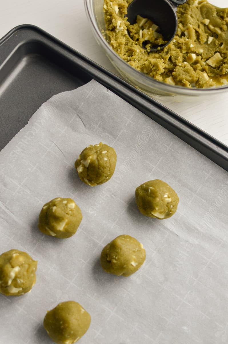 Rolling out matcha white chocolate cookie dough on a tray.