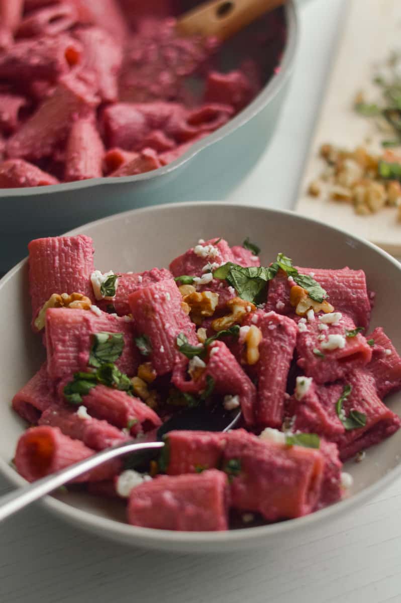 Beet pasta served in a bowl with feta and basil.