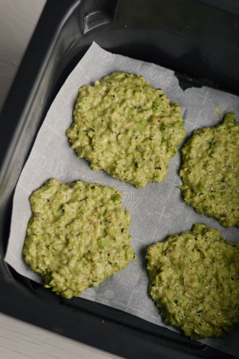 Shaping zucchini and edamame fritters on a tray.