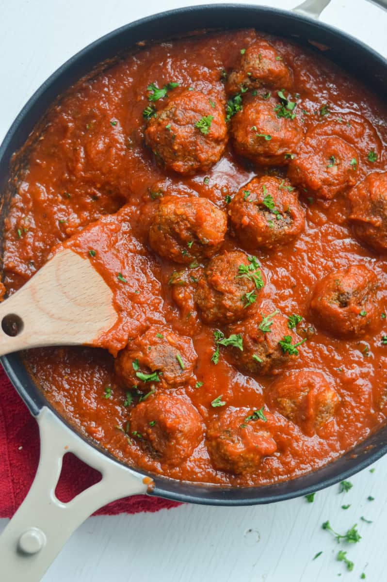 Tofu meatballs in a pan with tomato sauce.