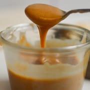 Taking a spoonful of vegan caramel from a jar.
