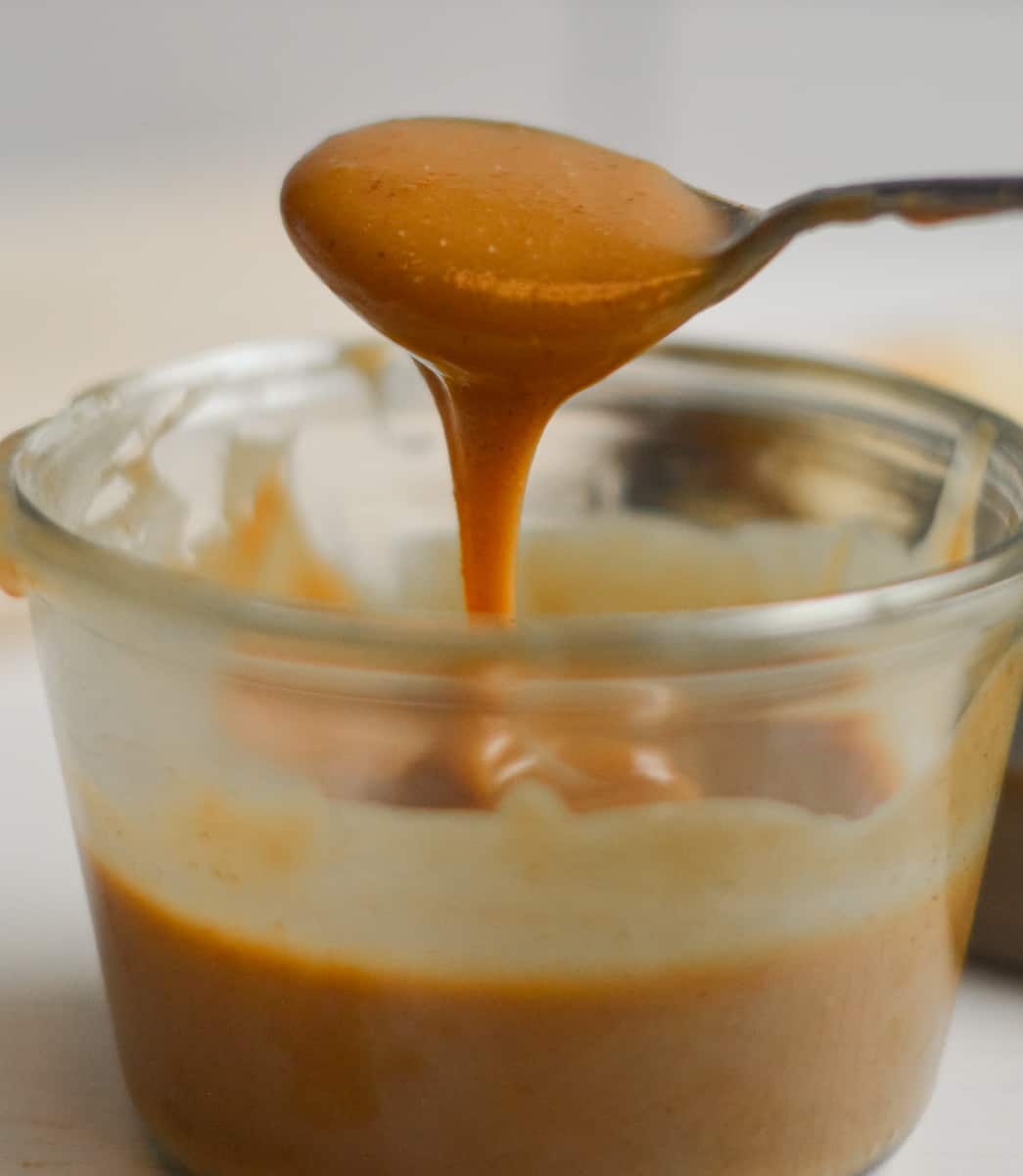 Taking a spoonful of peanut butter caramel from a jar.
