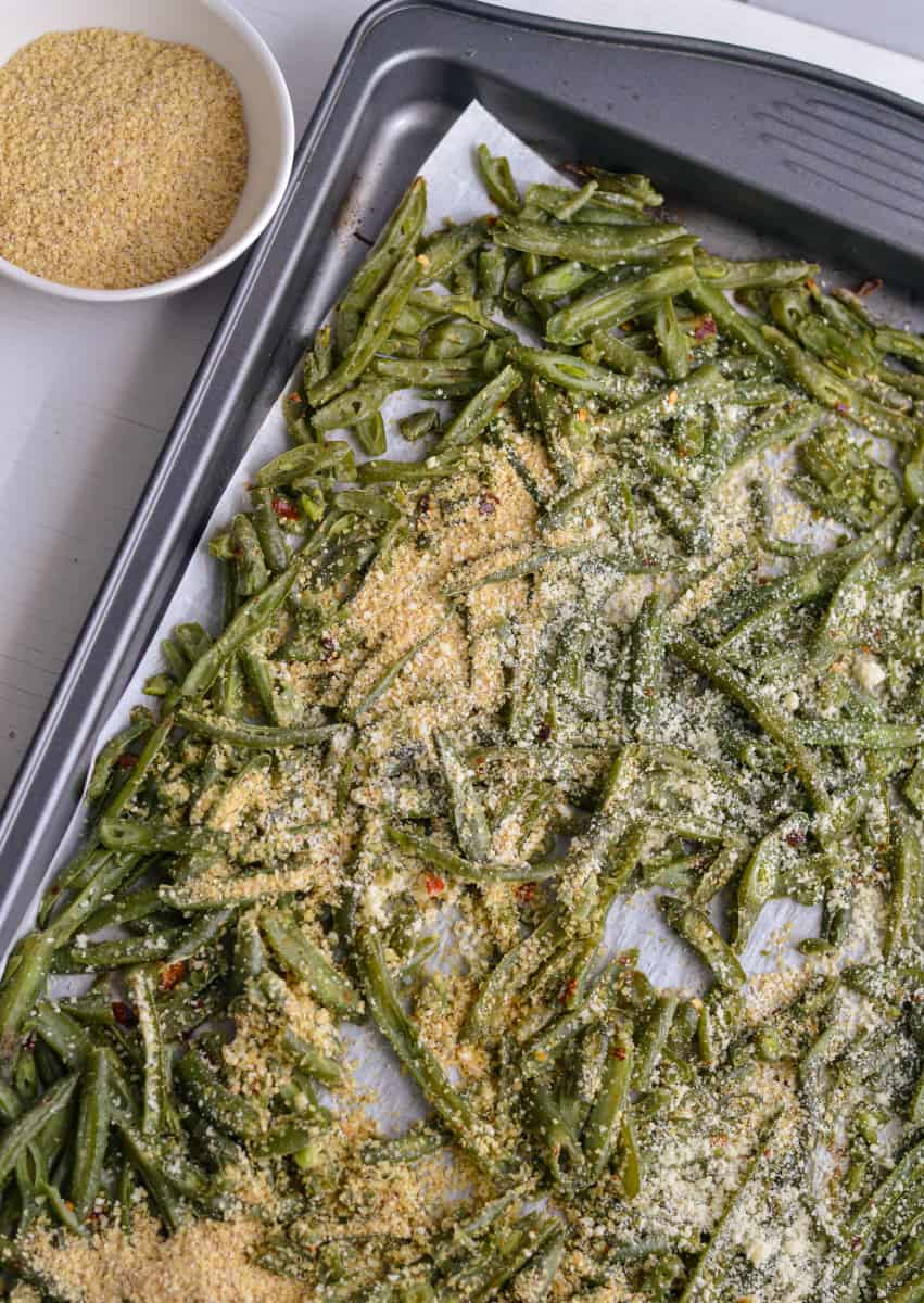 Adding parmesan to roasted green beans.