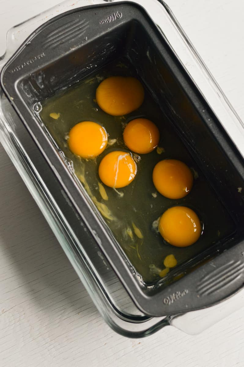 Cracking eggs into a loaf pan.