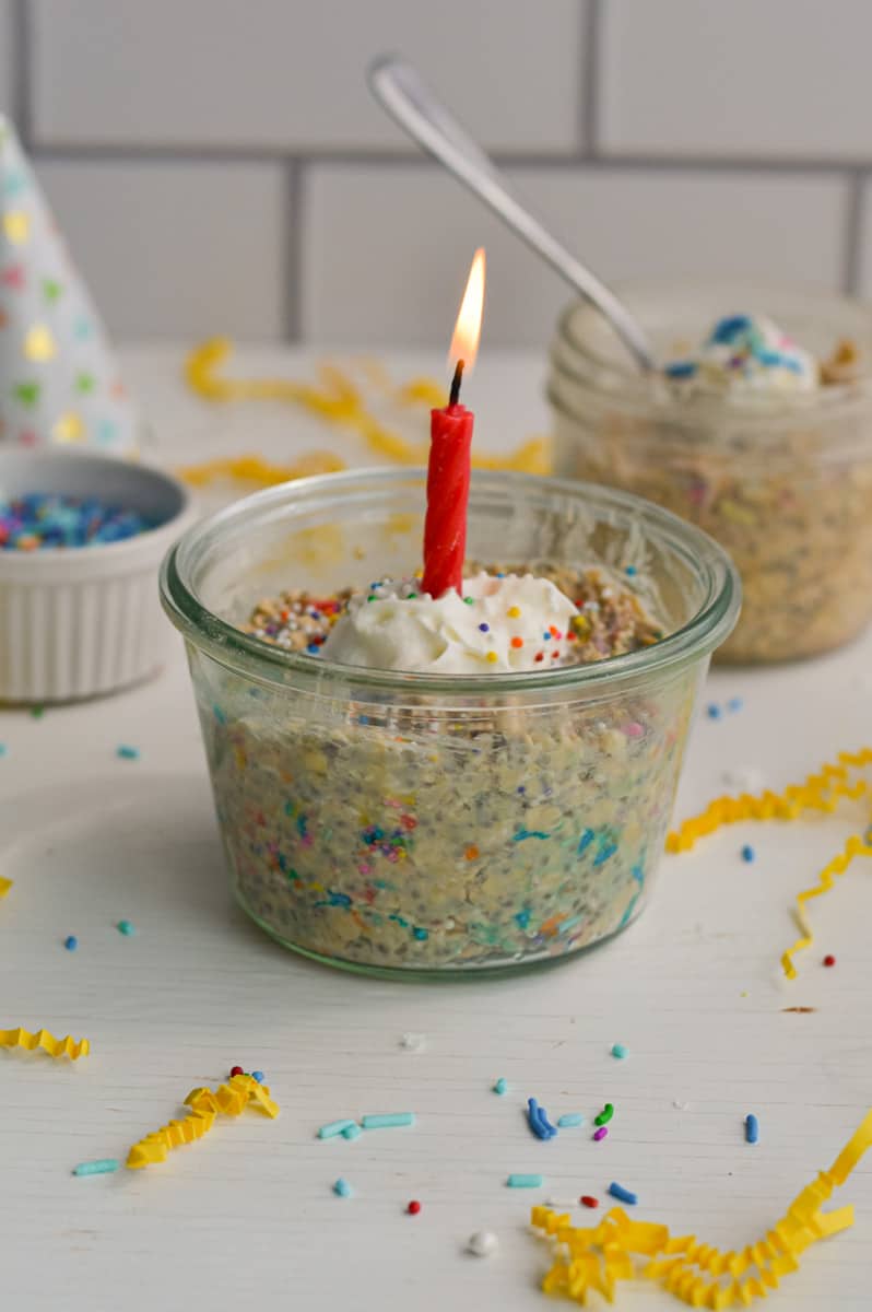 Birthday cake overnight oats with whipped cream and a candle.