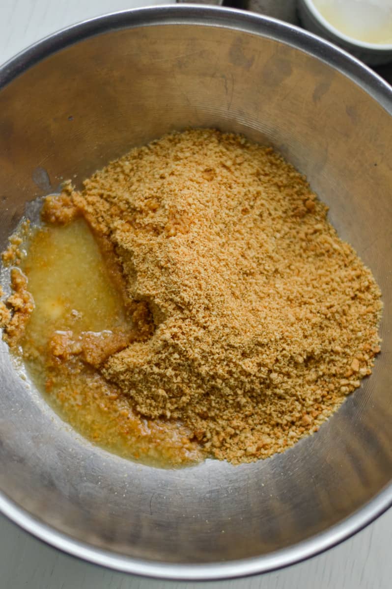 Mixing melted butter and cookie crumbs.