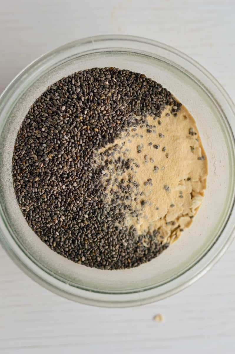 Adding oats, chia seeds and protein powder to a jar.
