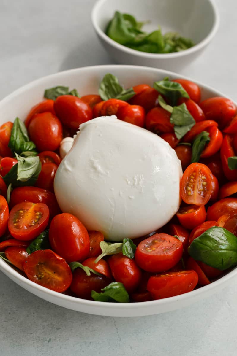Topping tomatoes with burrata and basil.