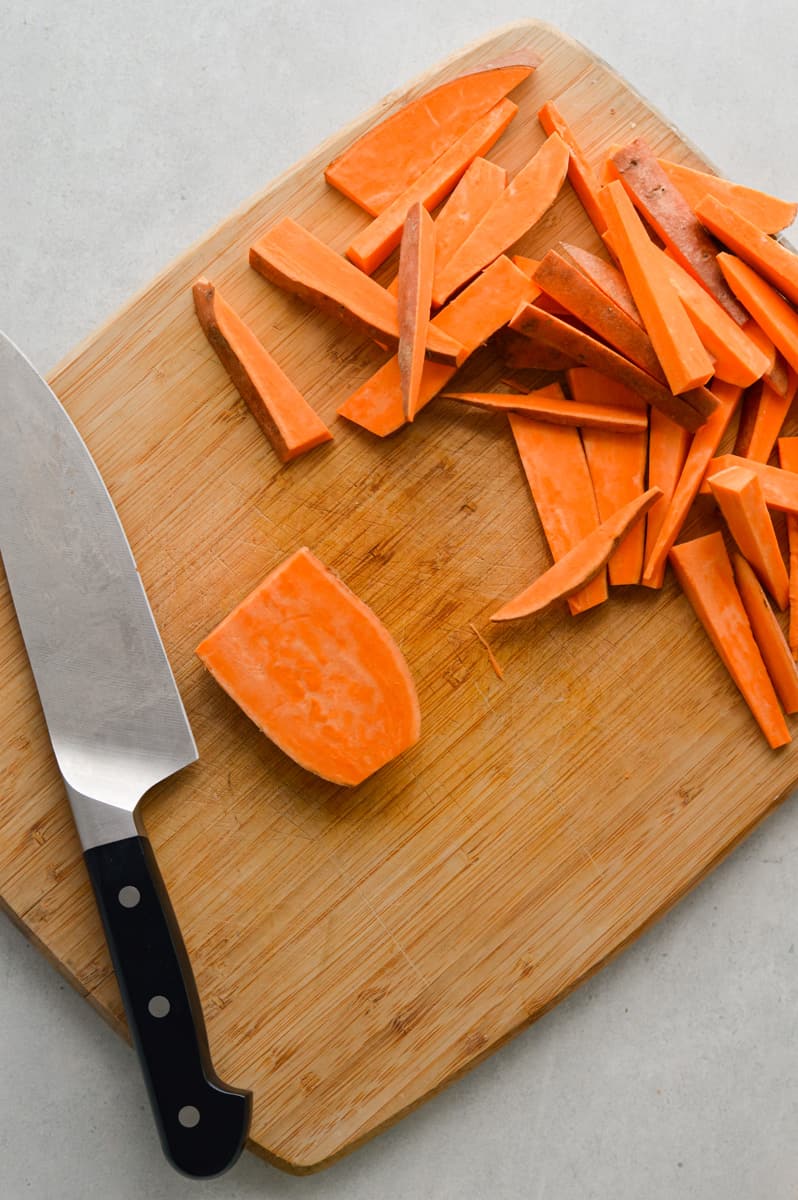Chopping sweet potatoes into wedges.
