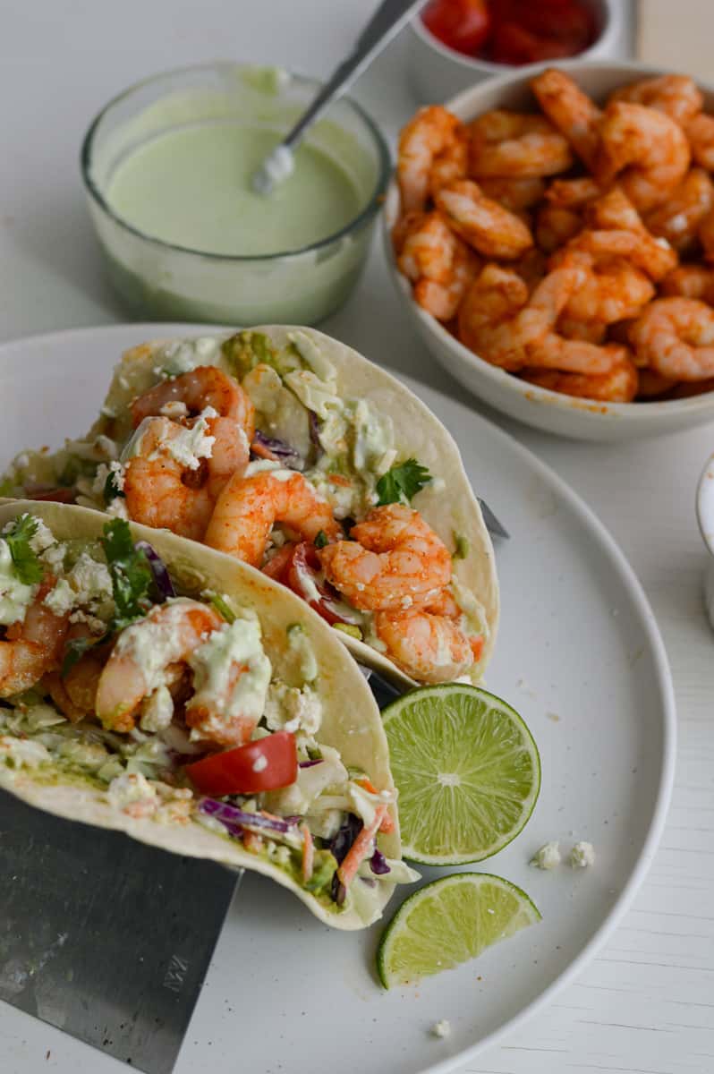 Close up of two shrimp tacos served with a lime slice.