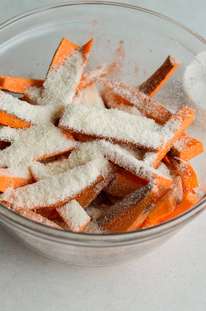 Coating sweet potatoes in spices and parmesan.