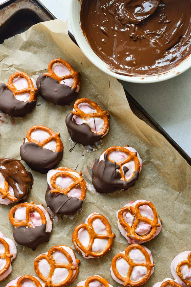 Dipping pretzel bites in melted chocolate.