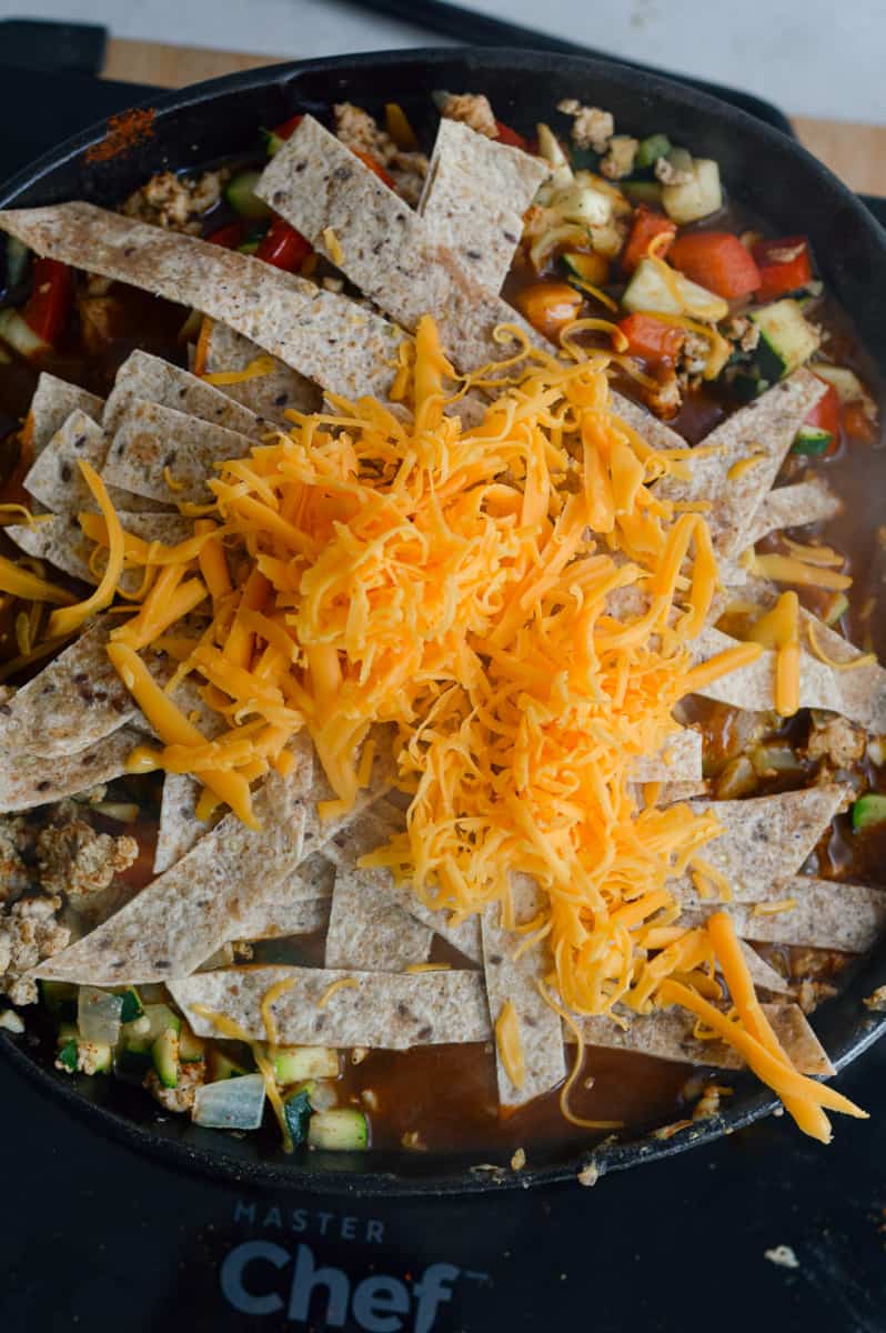 Layering tortilla strips and cheese on enchilada skillet.
