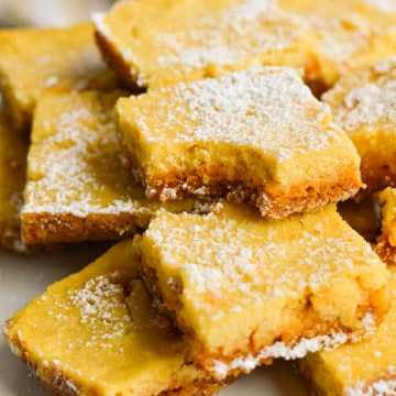 Plate of lemon bars with graham cracker crust with bites taken out.