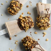 Four frozen yogurt bars coated in chocolate and peanuts.