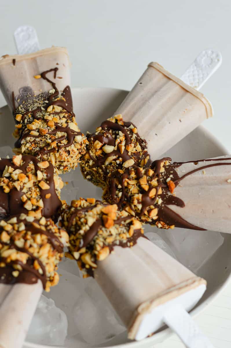 Plate of frozen yogurt bars with chocolate and peanuts.