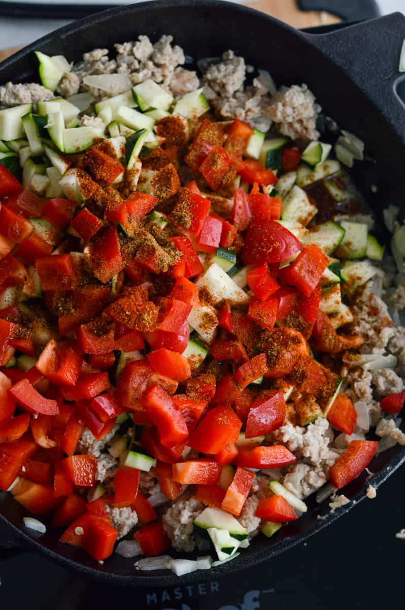 Sauteeing bell pepper and zucchini in a skillet.