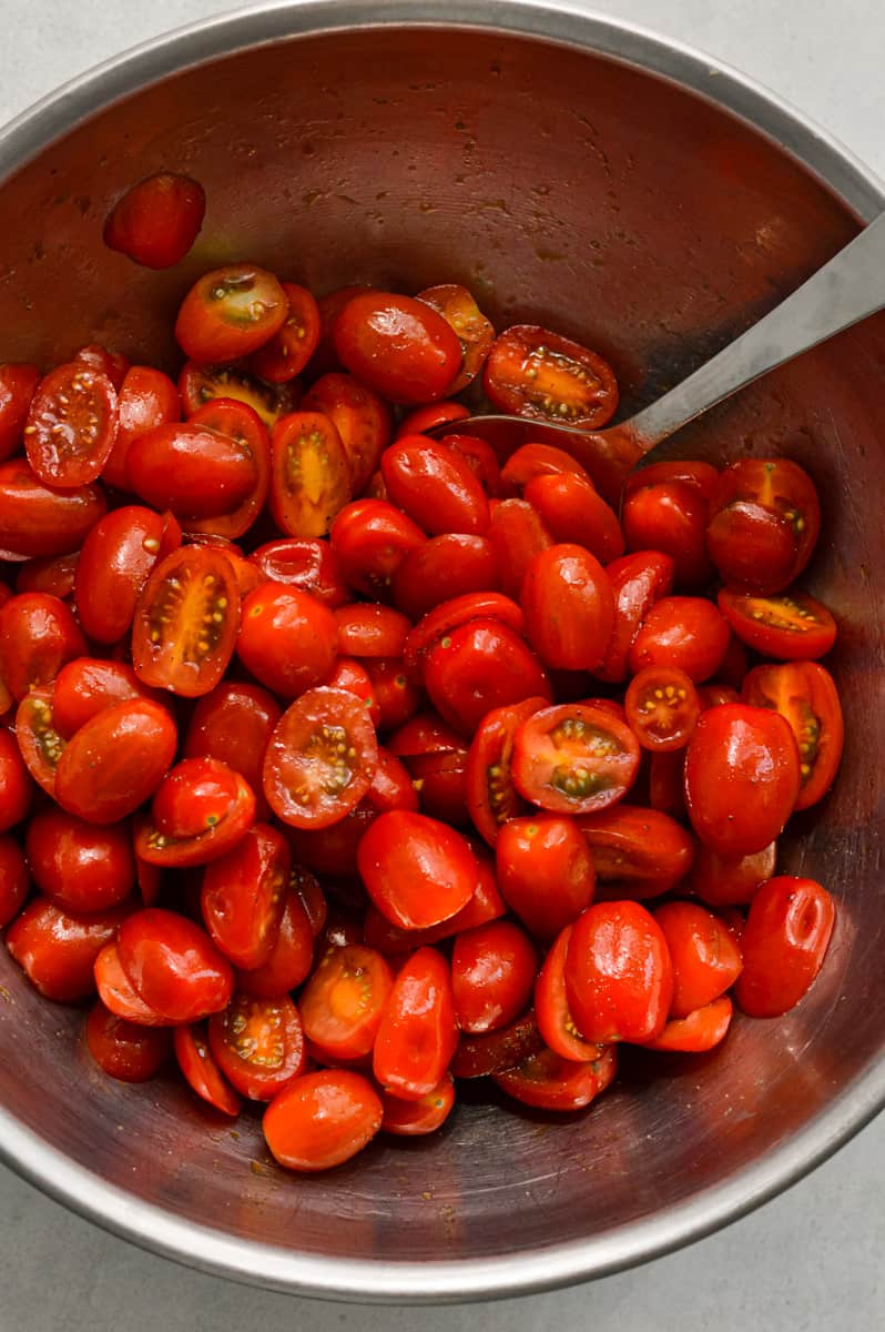 Mixing cherry tomatoes with olive oil, balsamic, salt and pepper.