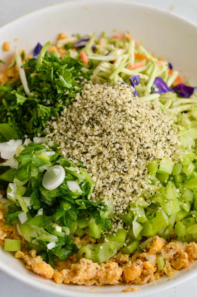 Adding chopped veggies and hemp seeds to chickpea salad.