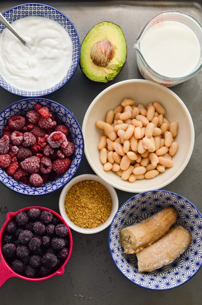 Ingredients including greek yogurt, white beans, berries, banana, flaxseed and avocado.