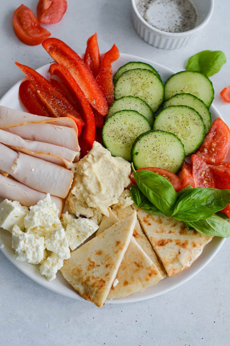 Snack plate ideas for a girl dinner including turkey, veggies, pita, hummus and cheese.