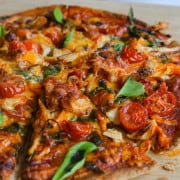 Air fryer tortilla pizza with cherry tomatoes, chicken, spinach, peppers and cheese.