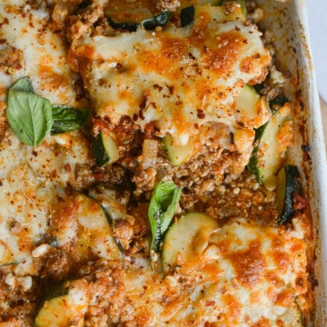 Close up of grounnd beef zucchini casserole topped with fresh basil.