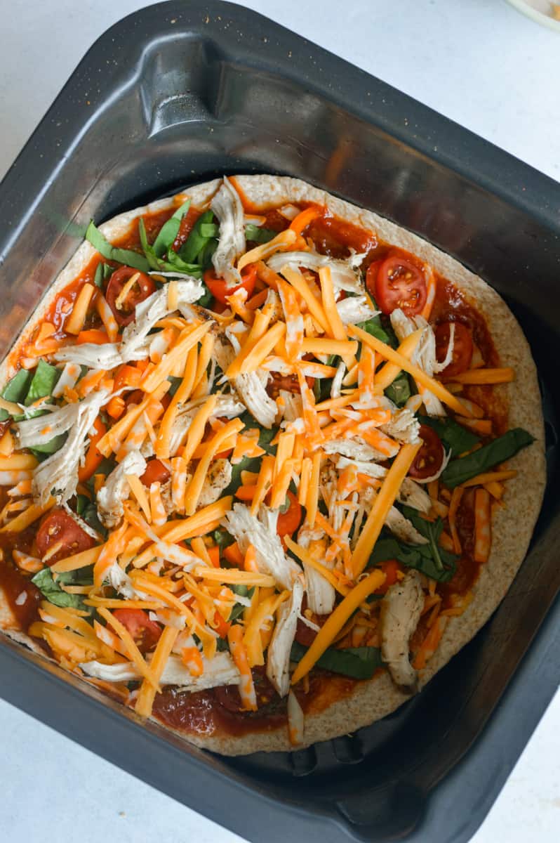 Cooking tortilla pizza in air fryer.
