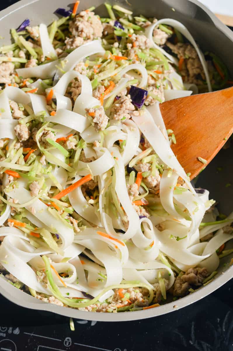 Adding coleslaw mix to the pan.