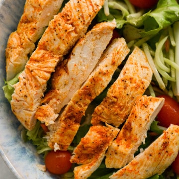 Baked thin sliced chicken breast on a salad.