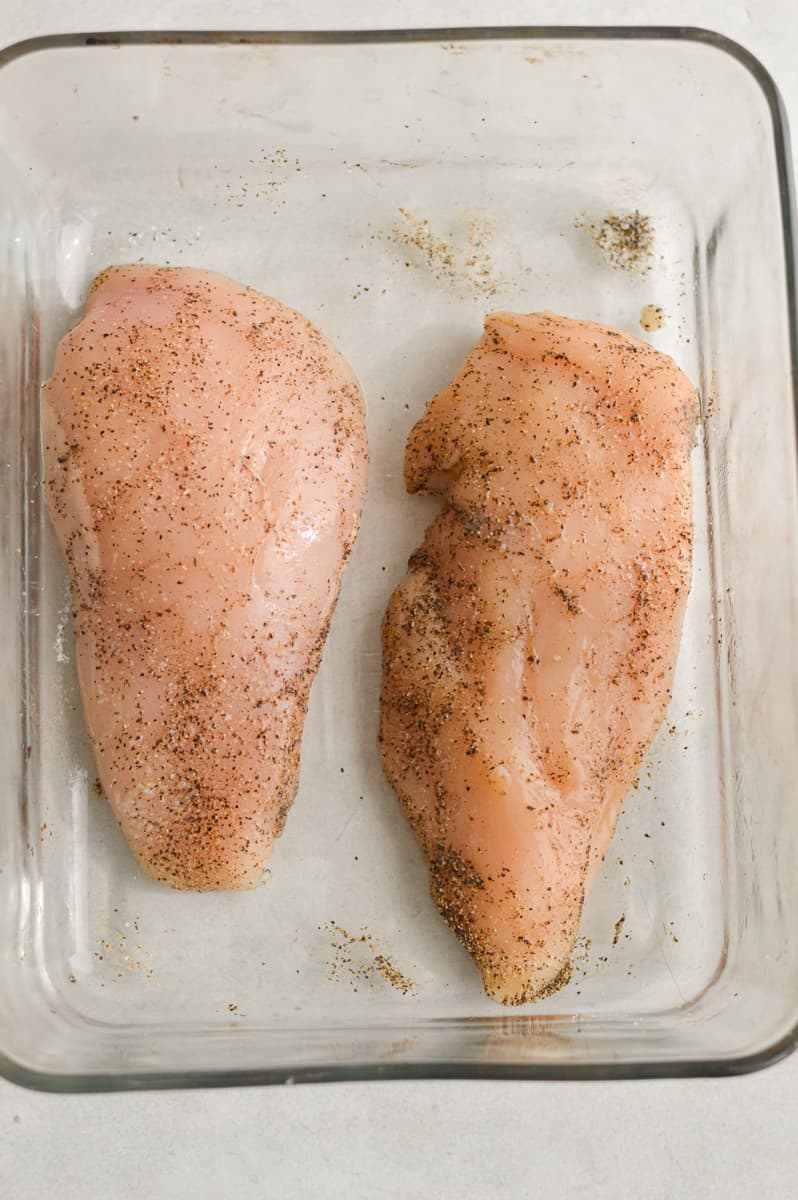 Two chicken breasts in a glass baking dish.
