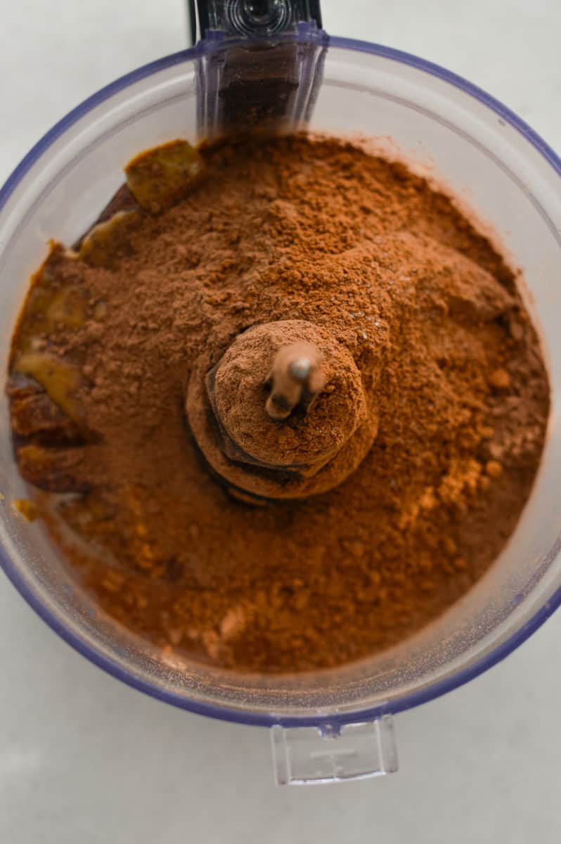 Adding dates, water, seed butter, chocolate protein powder, cocoa powder and salt to a food processor.