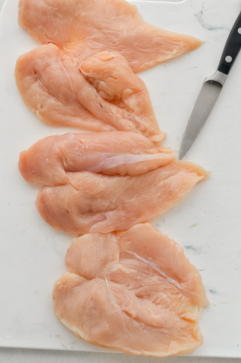 Thinly slicing chicken breasts.