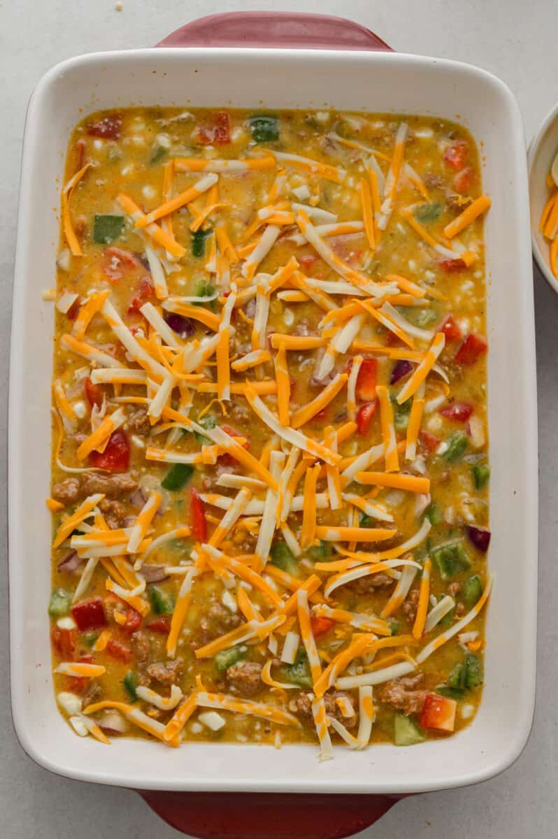 Sprinkling egg breakfast casserole with cheese.