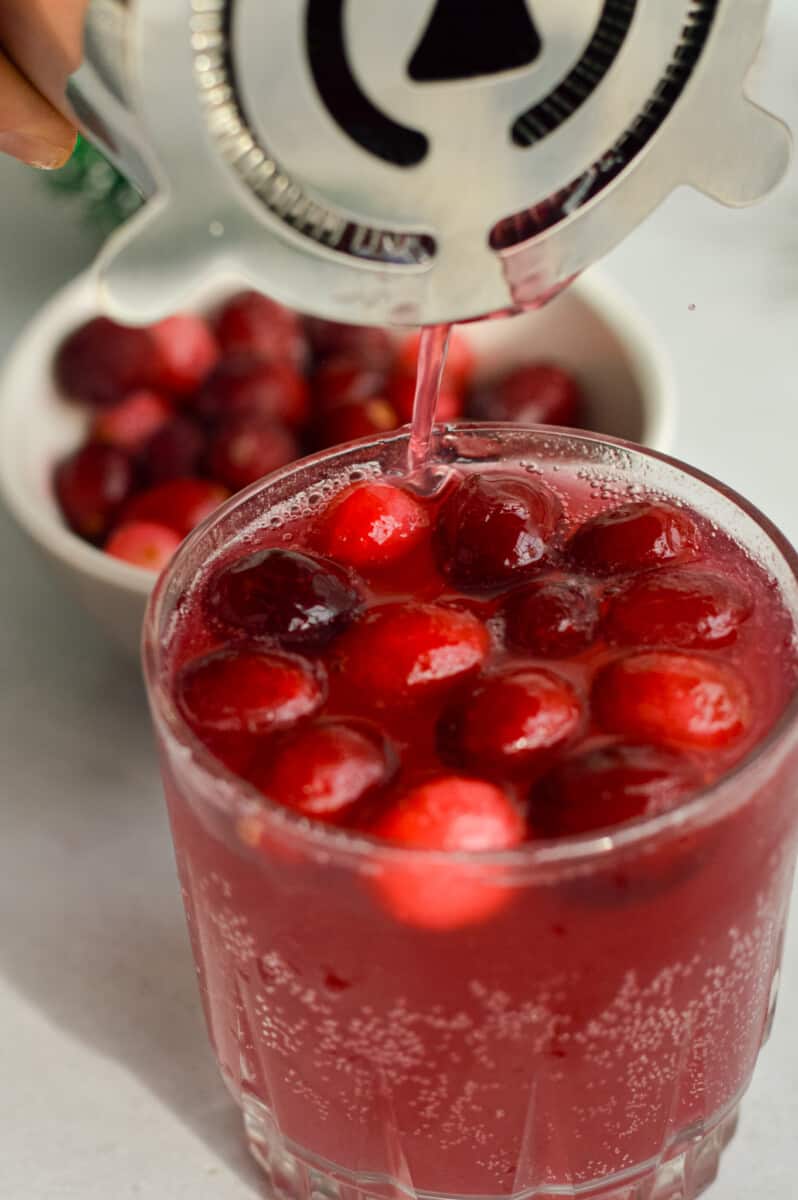 Topping cranberry mocktail with soda water.