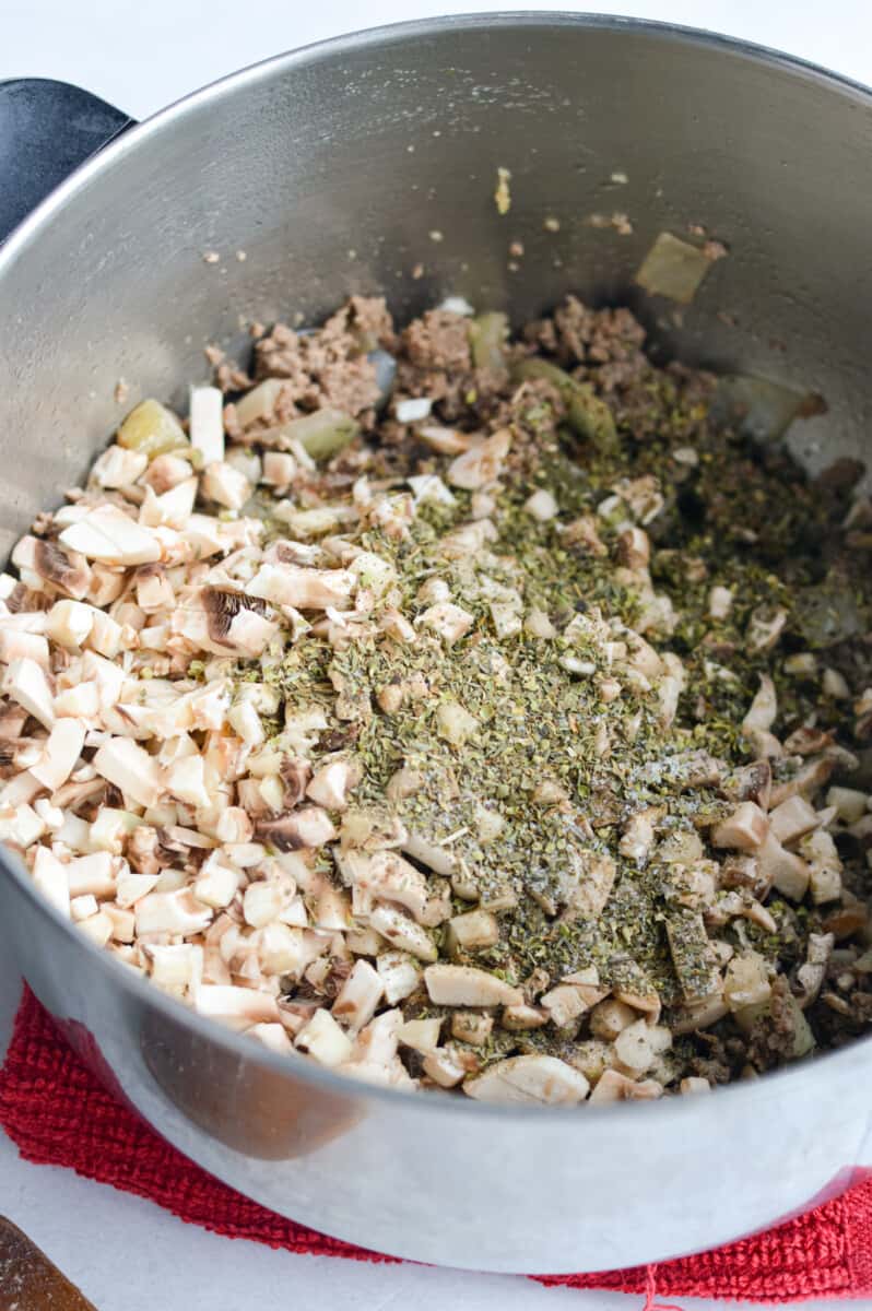 Adding diced mushrooms and seasoning to pot.