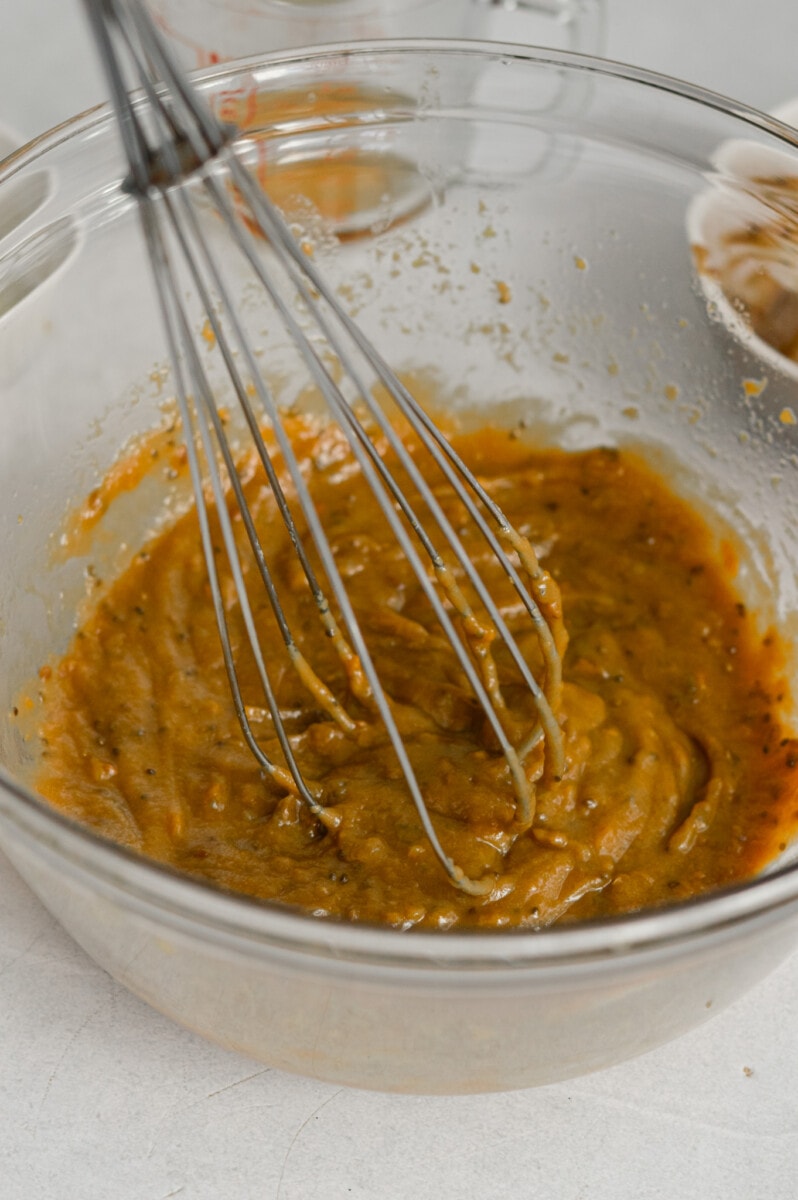 Whisking together almond butter, maple syrup, orange juice and orange zest in a bowl.