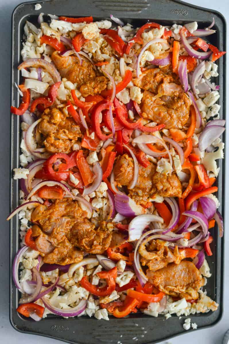 Arranging chicken thighs and vegetables on a sheet pan.