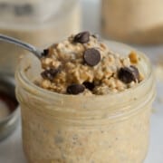 Spoon scooping cookie dough overnight oats out of a jar.